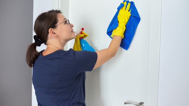 Vrouw gebruikt een allesreiniger spray voor haar deur